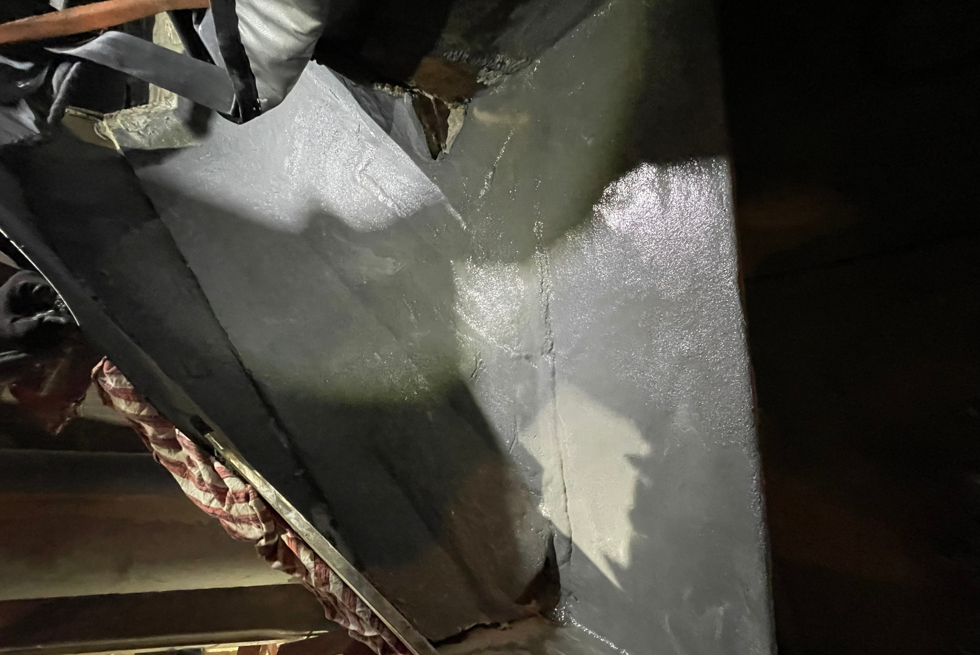 Detalhe de superfície metálica com revestimento protetor branco e cinzento parcialmente aplicado, mostrando processo de acabamento em componente industrial.